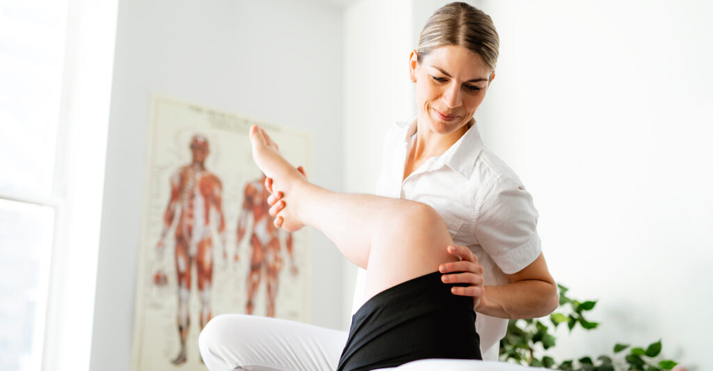 Femme kiné qui manipule la jambe d'un patient